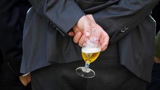 Ein Mann hält ein Glas mit Bier hinter seinem Rücken. (Foto: picture alliance / photothek | Thomas Trutschel)