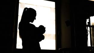 Schatten einer Frau mit Neugeborenem am Fenster einer Klinik (Foto: picture alliance/dpa | Sina Schuldt)